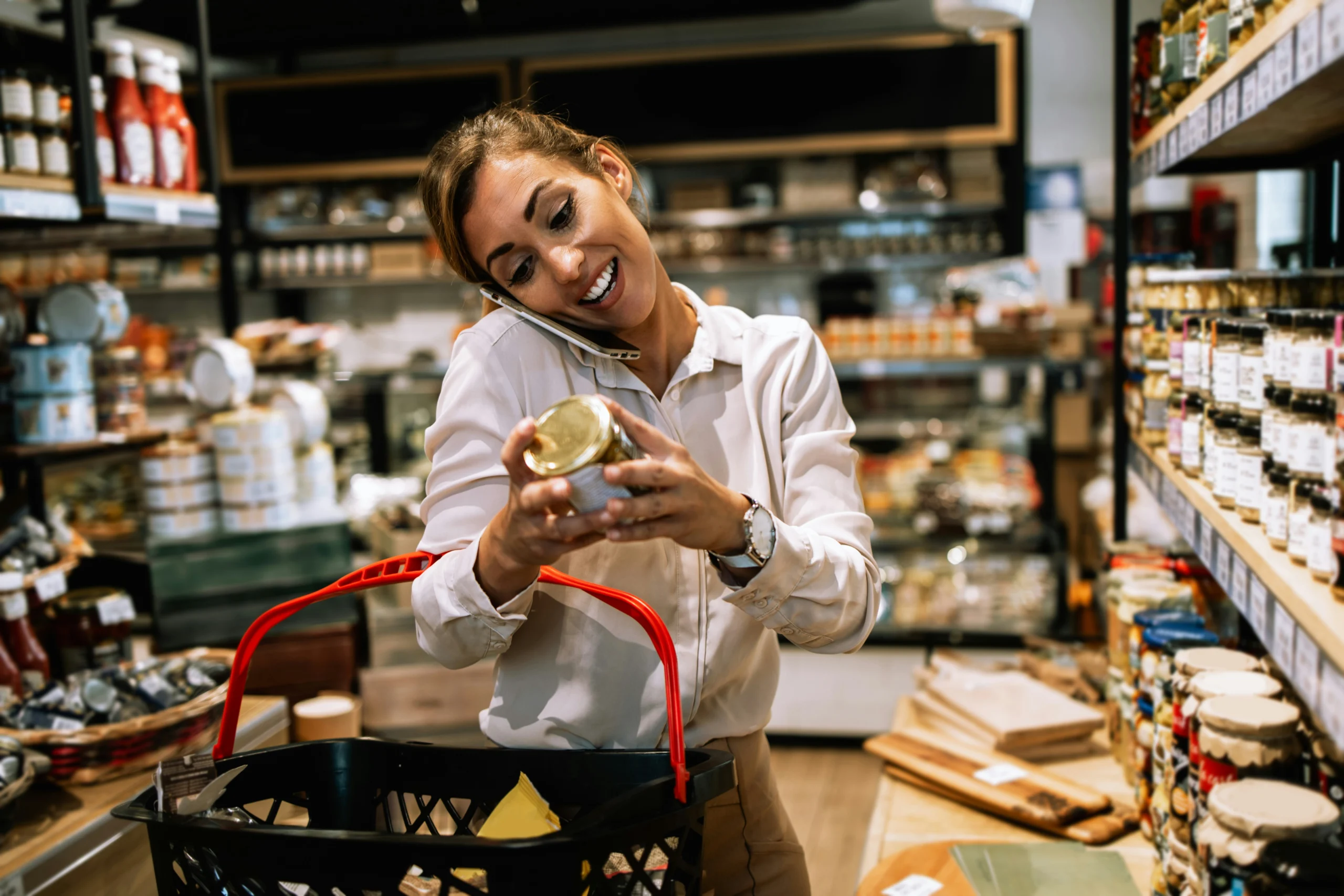 Kundin im Supermarkt prüft Produkt im Regal und telefoniert – Symbolbild für Shopper Research und Konsumentenverhalten bei TeamQ