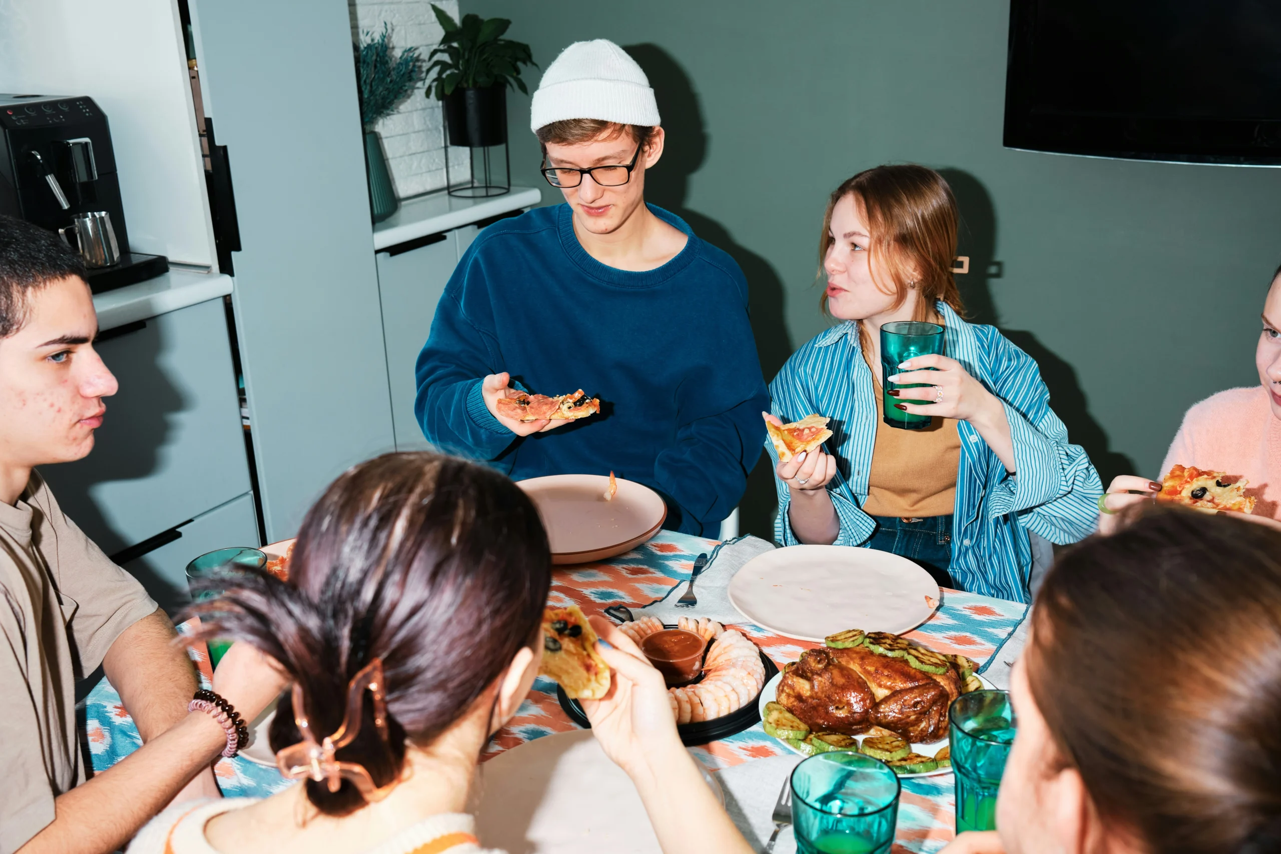 Freunde essen gemeinsam Pizza am Tisch – Alltagssituation und Consumer Insights.