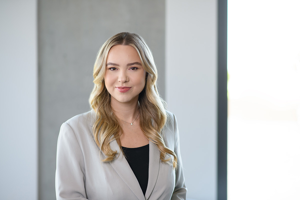 Porträt einer TeamQ-Mitarbeiterin – Businessfoto mit grauem Blazer im Büro.