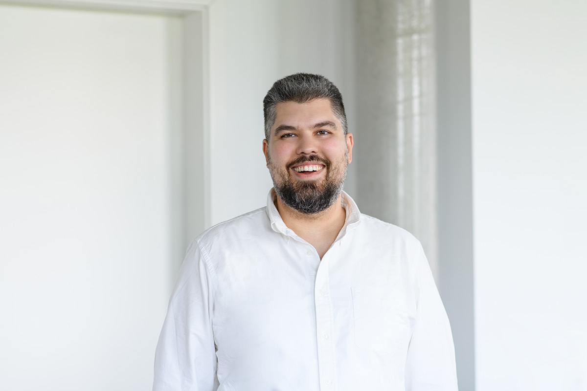 Porträt eines TeamQ-Mitarbeiters im Büro – lächelndes Businessfoto in weißem Hemd.